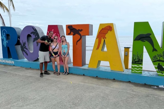 Guests posing at the colorful ROATÁN sign