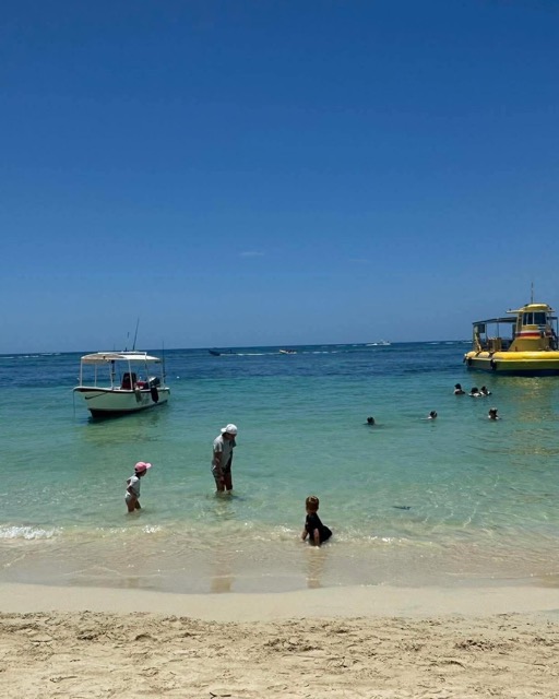 Boats floating just off a white-sand beach